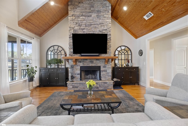 living room featuring light hardwood / wood-style flooring, wood ceiling, and a stone fireplace