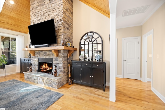 bar with a high ceiling, crown molding, a stone fireplace, and light hardwood / wood-style flooring