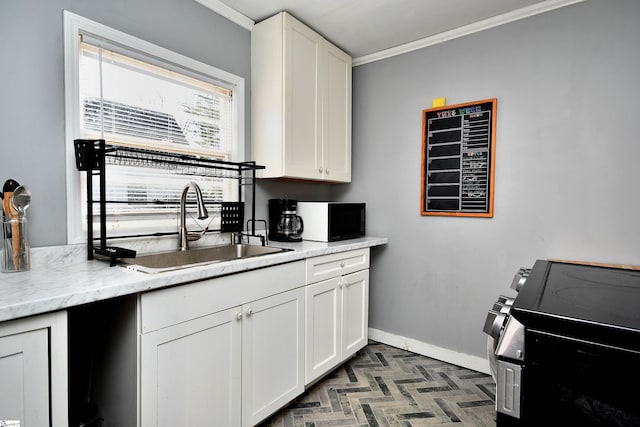 kitchen with light stone countertops, white cabinetry, crown molding, and sink