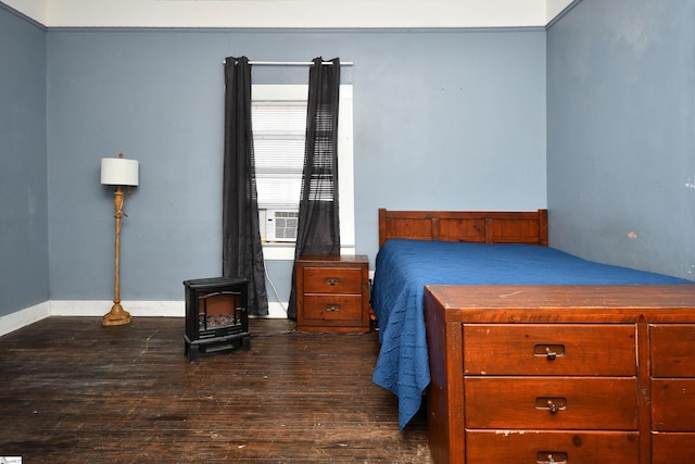 bedroom with a wood stove, dark hardwood / wood-style flooring, and cooling unit