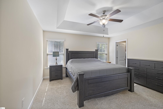 carpeted bedroom with a raised ceiling and ceiling fan