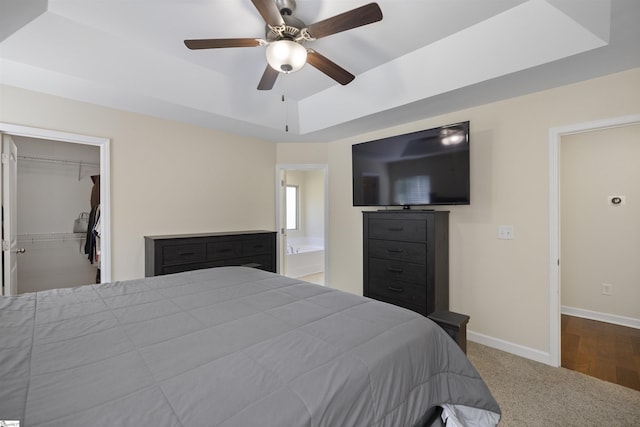 bedroom with a tray ceiling, a walk in closet, and ceiling fan