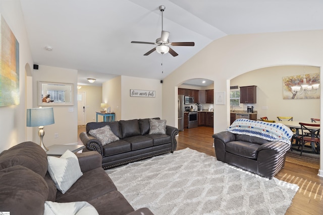 living room with ceiling fan with notable chandelier, wood-type flooring, and vaulted ceiling