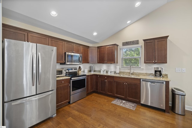 kitchen featuring lofted ceiling, dark wood-type flooring, sink, light stone countertops, and stainless steel appliances