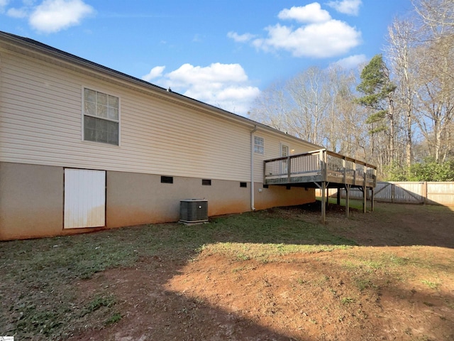 view of home's exterior featuring central air condition unit, a wooden deck, and a yard