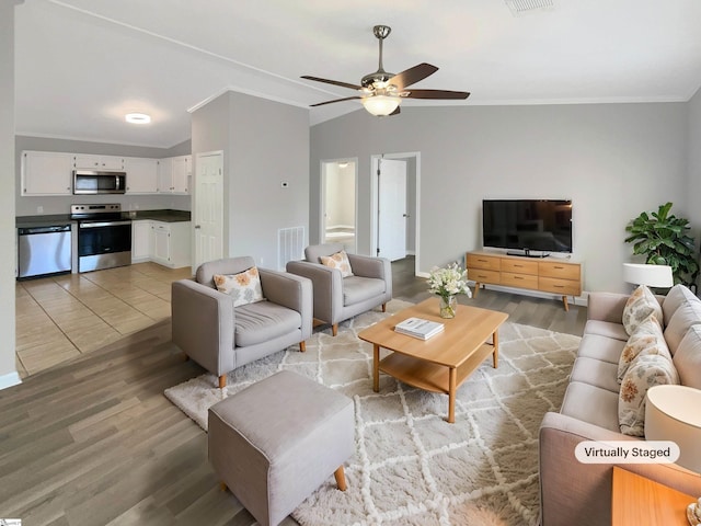 living room featuring ceiling fan, hardwood / wood-style floors, vaulted ceiling, and ornamental molding