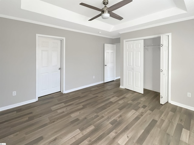 unfurnished bedroom featuring ceiling fan, dark wood-type flooring, and a tray ceiling