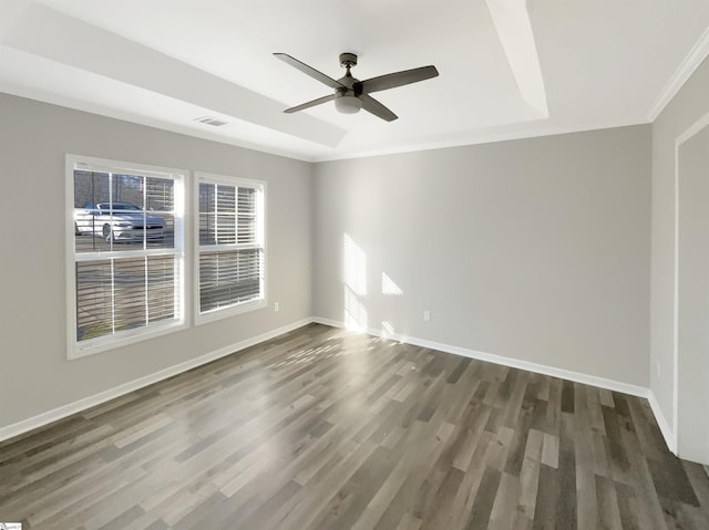 unfurnished room with a raised ceiling, ceiling fan, dark hardwood / wood-style flooring, and ornamental molding