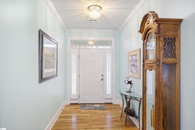 entrance foyer with a notable chandelier, light wood-type flooring, and crown molding