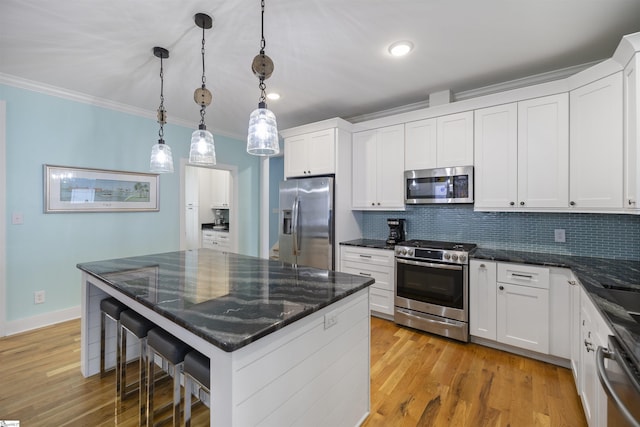 kitchen with white cabinetry, tasteful backsplash, pendant lighting, a kitchen bar, and appliances with stainless steel finishes