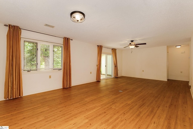 empty room with a textured ceiling, ceiling fan, and hardwood / wood-style floors