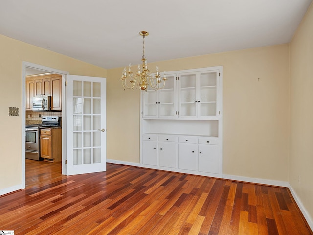 unfurnished dining area featuring dark wood-type flooring and an inviting chandelier