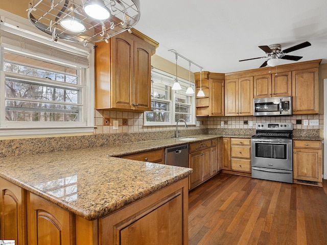 kitchen with light stone countertops, dark hardwood / wood-style flooring, decorative light fixtures, decorative backsplash, and appliances with stainless steel finishes