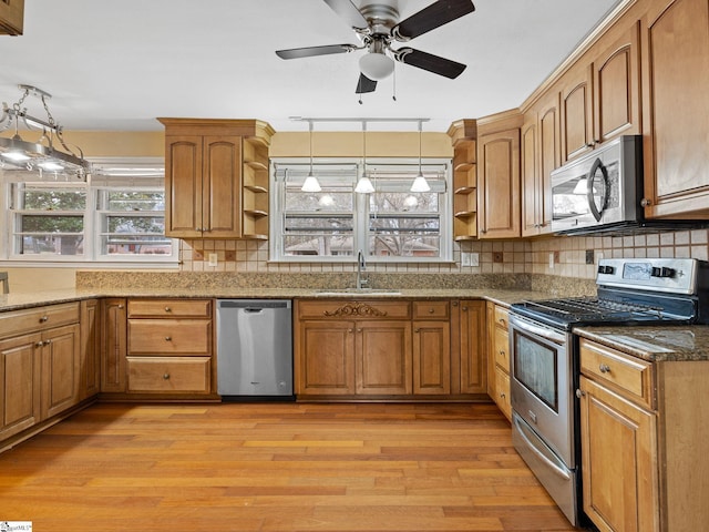 kitchen with backsplash, hanging light fixtures, sink, and appliances with stainless steel finishes