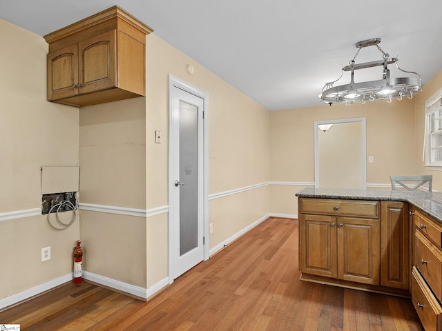 kitchen with light stone countertops, wood-type flooring, and hanging light fixtures