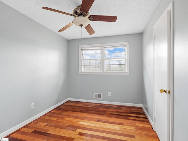 unfurnished room with ceiling fan, light wood-type flooring, and a textured ceiling