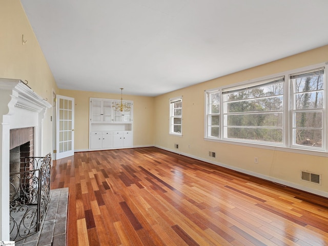 unfurnished living room featuring a fireplace, wood-type flooring, and an inviting chandelier