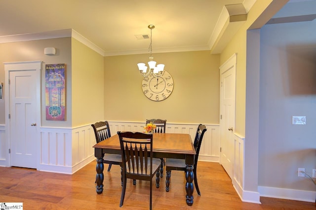 dining space with ornamental molding, light hardwood / wood-style flooring, and an inviting chandelier