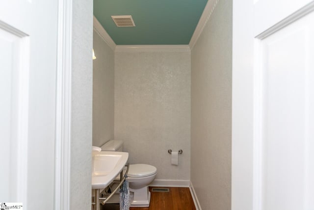 bathroom with hardwood / wood-style floors, toilet, ornamental molding, and sink