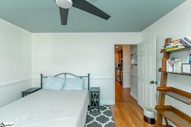 bedroom featuring light hardwood / wood-style floors, ceiling fan, and ornamental molding