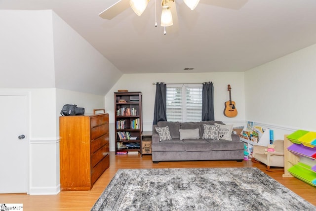 living room with ceiling fan, wood-type flooring, and vaulted ceiling