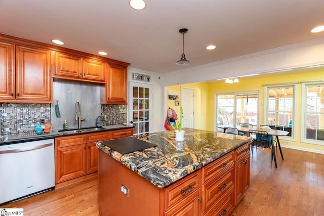 kitchen featuring dishwasher, sink, hanging light fixtures, light hardwood / wood-style floors, and decorative backsplash