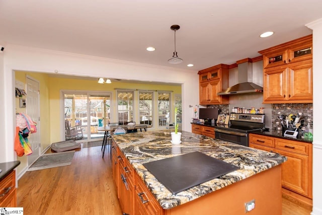 kitchen featuring tasteful backsplash, wall chimney range hood, pendant lighting, a kitchen island, and stainless steel range with electric cooktop