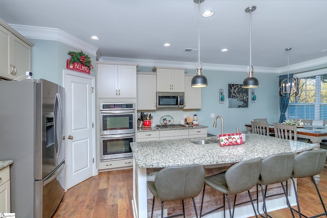 kitchen with backsplash, a center island with sink, sink, appliances with stainless steel finishes, and decorative light fixtures