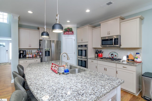 kitchen featuring decorative light fixtures, sink, an island with sink, and appliances with stainless steel finishes