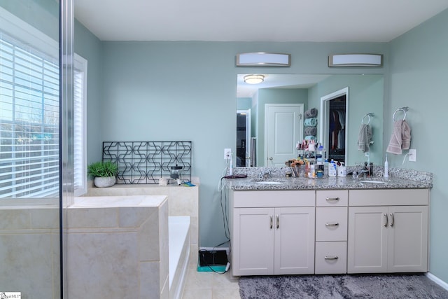 bathroom featuring tile patterned flooring, vanity, and tiled bath