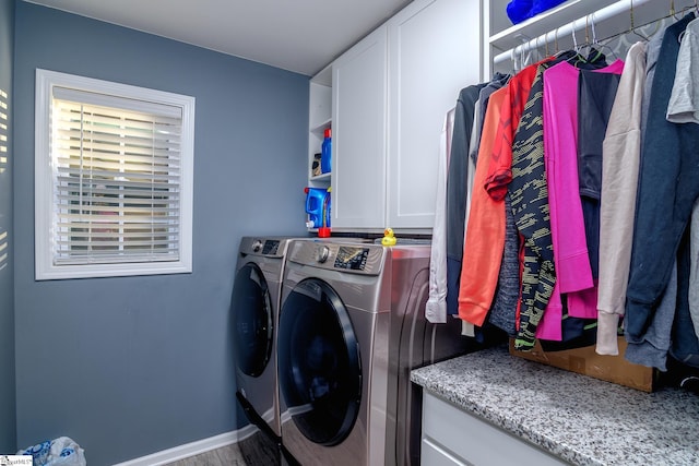 clothes washing area with washer and clothes dryer, cabinets, and hardwood / wood-style flooring