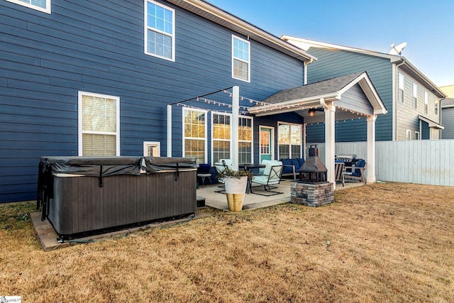 rear view of house with a patio area, a yard, and a hot tub