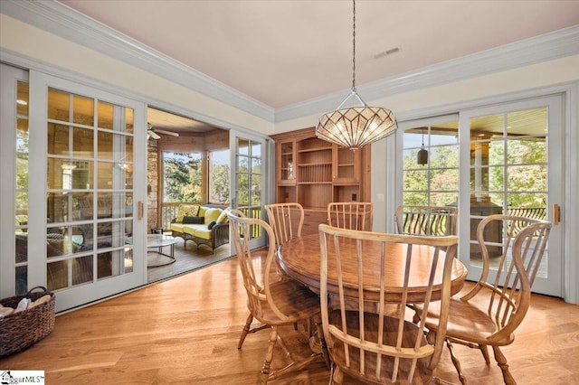 dining area with ornamental molding, a wealth of natural light, and light hardwood / wood-style flooring