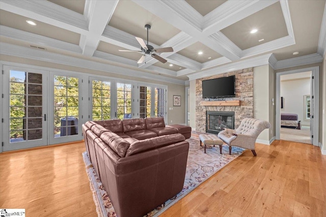 living room with beam ceiling, french doors, coffered ceiling, a stone fireplace, and crown molding