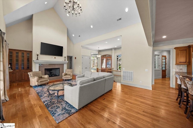 living room with light wood-type flooring, a towering ceiling, and a notable chandelier