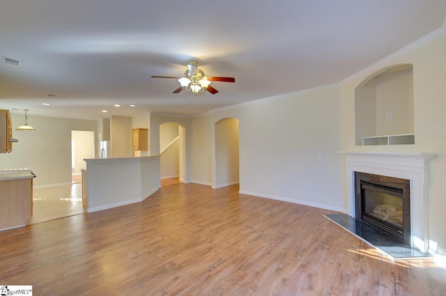 unfurnished living room featuring ceiling fan, light wood-type flooring, and ornamental molding