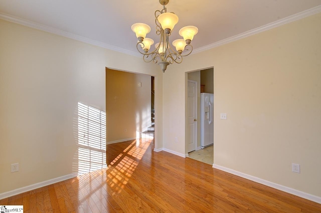 empty room featuring light wood-type flooring, ornamental molding, and an inviting chandelier