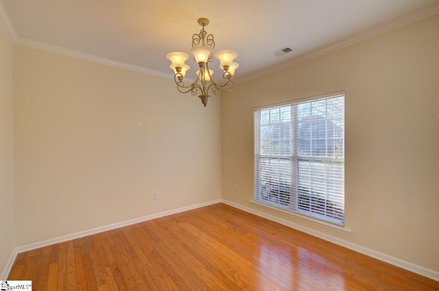 spare room with ornamental molding, wood-type flooring, and an inviting chandelier