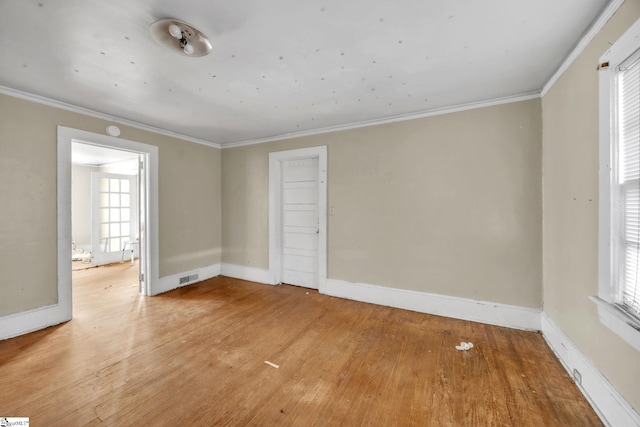 unfurnished room featuring hardwood / wood-style floors, crown molding, and a wealth of natural light