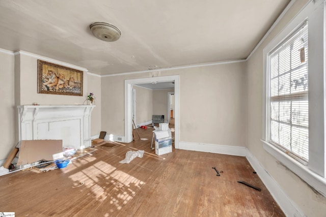 unfurnished living room featuring wood-type flooring, a wealth of natural light, and crown molding