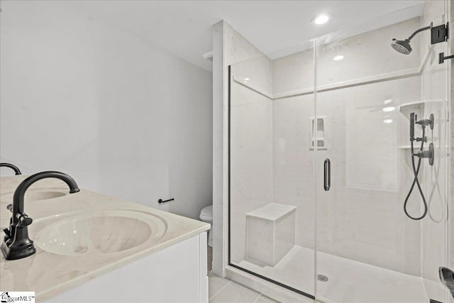 bathroom featuring tile patterned floors, vanity, a shower with shower door, and toilet