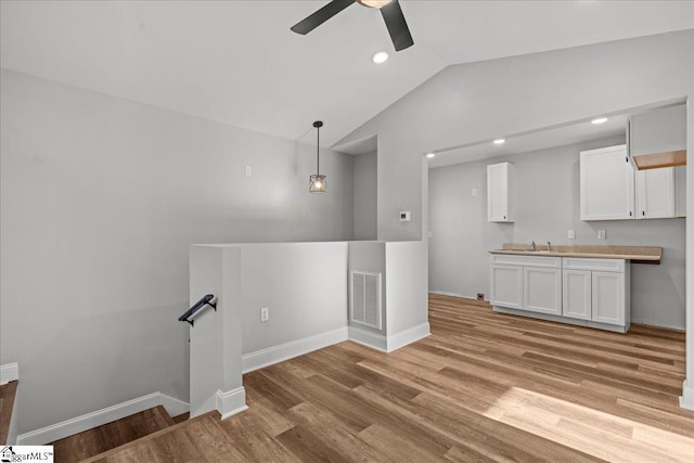 unfurnished living room featuring ceiling fan, light wood-type flooring, lofted ceiling, and sink