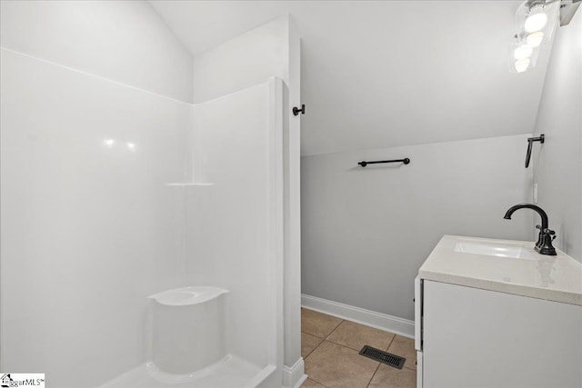 bathroom with tile patterned floors, vanity, and vaulted ceiling