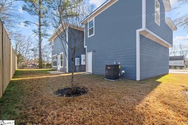 view of side of home with central air condition unit and a lawn