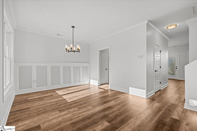 spare room featuring a chandelier, dark hardwood / wood-style flooring, and crown molding