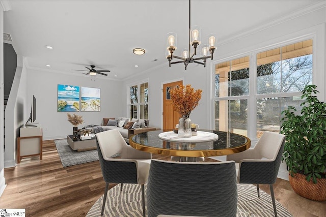 dining room featuring hardwood / wood-style floors, ceiling fan with notable chandelier, and crown molding