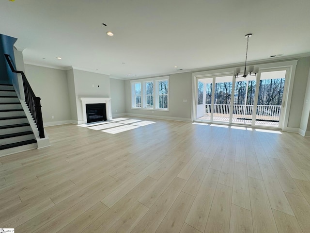 unfurnished living room with an inviting chandelier, crown molding, and light hardwood / wood-style flooring