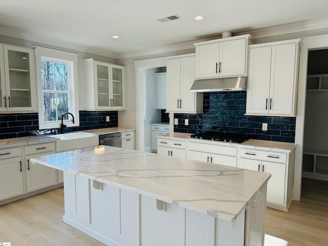 kitchen with white cabinets, a kitchen island, light stone counters, and gas cooktop