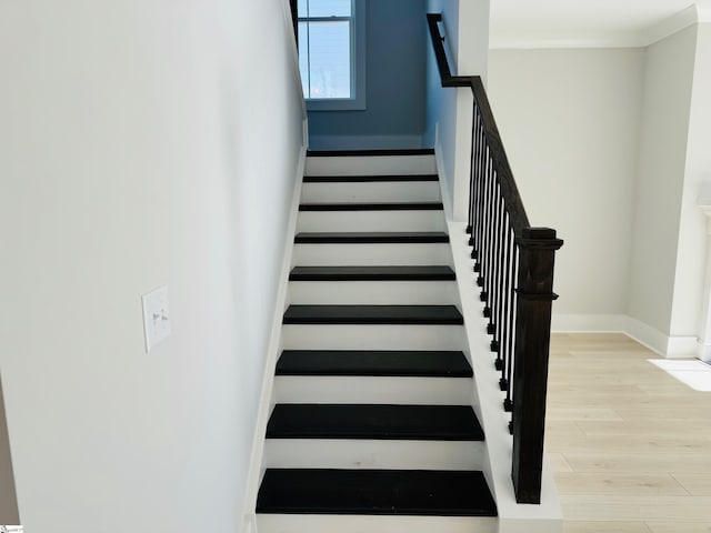 stairway with hardwood / wood-style floors and ornamental molding