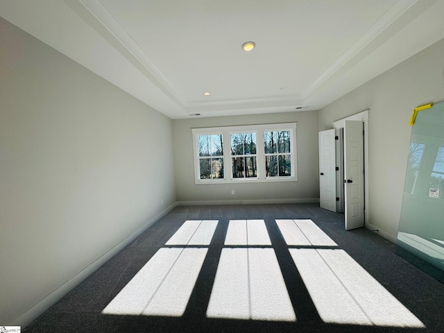 carpeted spare room with a raised ceiling